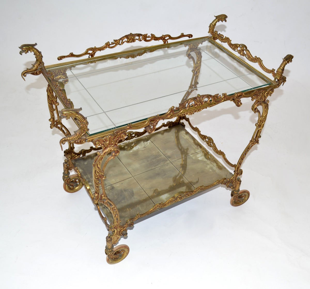 Ornate brass Baroque-style cart or tea trolley in ornate brass, glass and silvered-mirror with original wooden wheels. Overall height 26