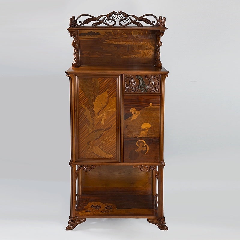 A French Art Nouveau walnut cabinet with fruitwood and rosewood inlay and bronze and carved decoration by Emile Gallé. The cabinet features a carved dragonfly and vegetal design, two cupboards and a short drawer mounted with a bronze escutcheon and