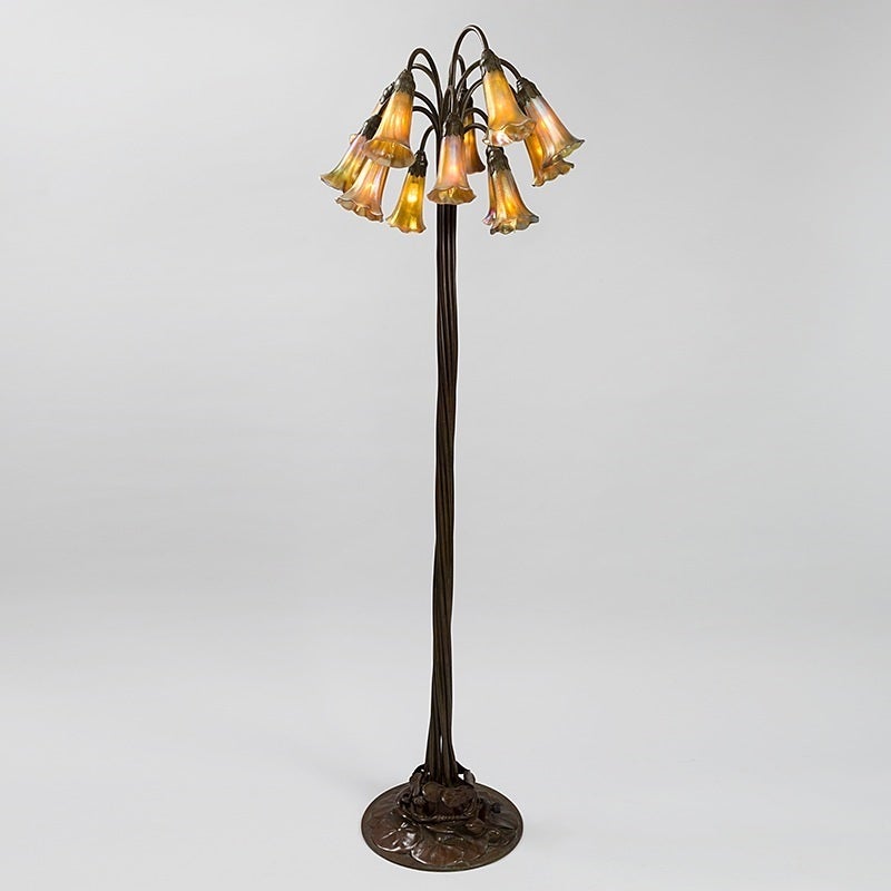 Tiffany Studios 12-light lily floor lamp. The floor lamp has a bronze lily pad base with 12 twisted stems each terminating with a beautiful gold iridescent Favrile lily shade. Each shade has a lightly ribbed body and the base is finished in a rich