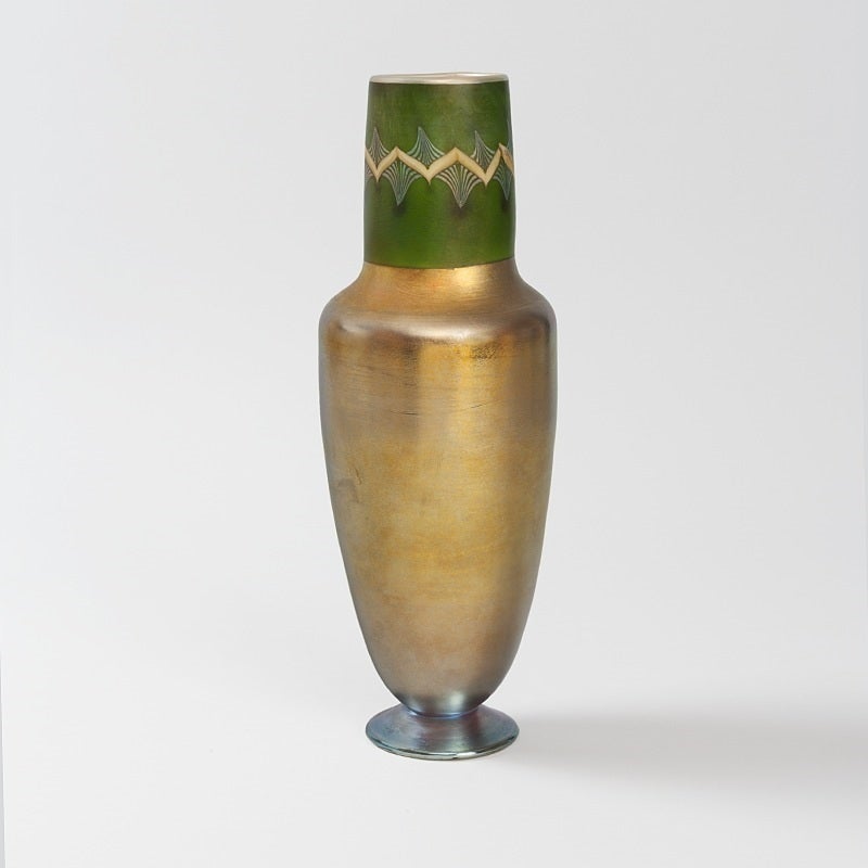 A Tiffany Studios New York golden favrile glass vase with an upper green border ornamented with pulled decoration by Louis Comfort Tiffany, circa 1915.

Signed, 