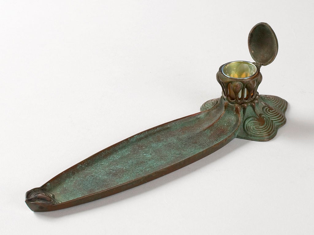A Tiffany Studios, New York patinated bronze inkwell and pen tray with favrile glass insert.

