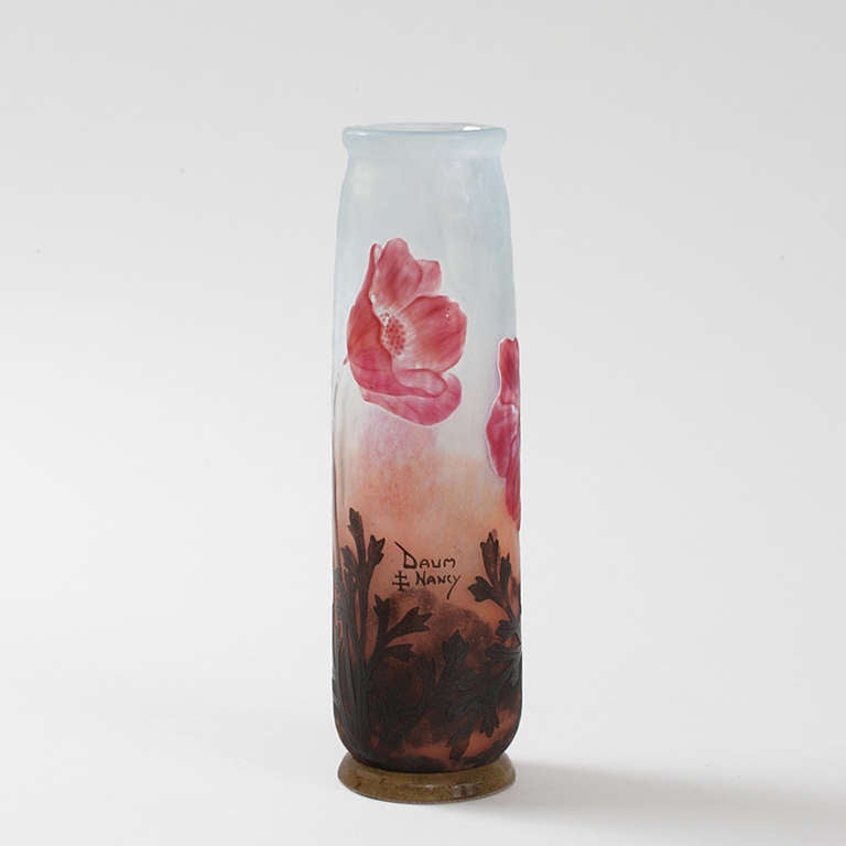 A French Art Nouveau cameo glass vase by Daum, comprised of three pinkish-red poppy flowers wheel carved to show different stages of bloom, against a sky blue martelé  technique background, with brown foliage and peach tones towards the bottom to