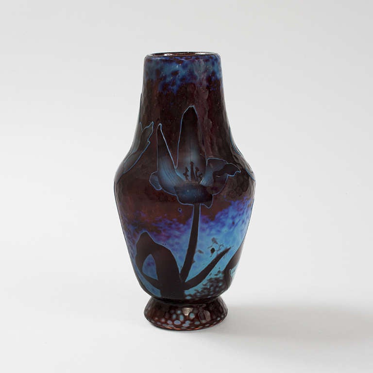 A French Art Nouveau wheel-carved cameo footed glass vase by Daum. Deep purple flowers are featured against a plum and blue martelé background. Circa 1900.

Signed, 