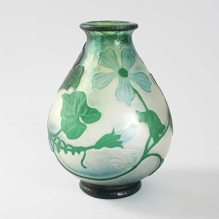A French Art Nouveau clear glass vase with green cameo overlay in a squash blossom motif by Daum. The vase has deep green leaves, buds, flowers and a squash suspended from sinuous vines, circa 1900.

A vase with similar decoration is pictured in: