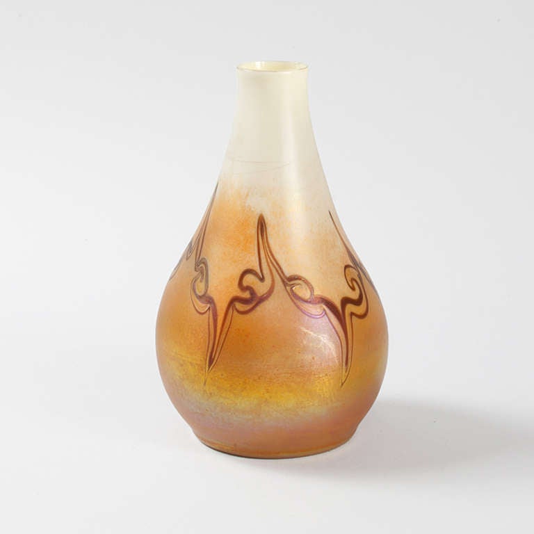 A Tiffany Studios New York favrile vase with pulled decoration.  The vase has an iridescent background graduating from opalescent through yellow and pink to orange, with dark red swirls. Signed, 