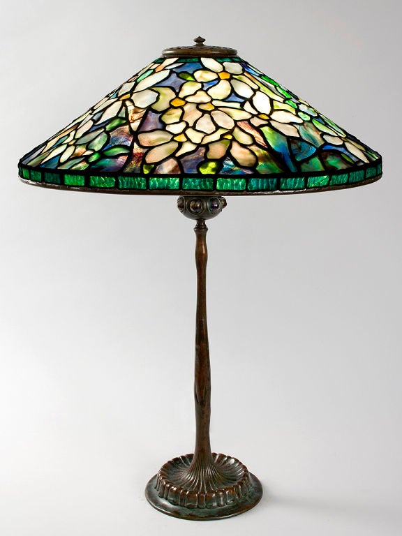 A Tiffany Studios New York glass and bronze “Clematis” table lamp, featuring multi-hued glass  depicting clematis flowers, atop a patinated bronze “Jeweled” base.