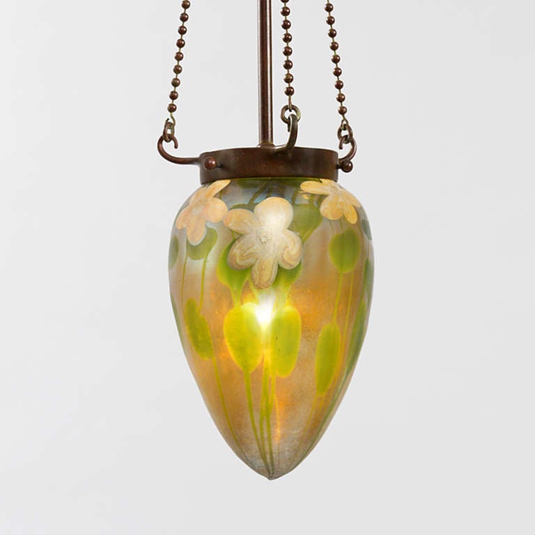 A Tiffany Studios New York decorated Favrile glass “Stalactite” shade. The shade features a band of yellow and white applied water flowers  with delicately carved pistils and stamens. The flowers are surrounded by a lily pad and vine motif against