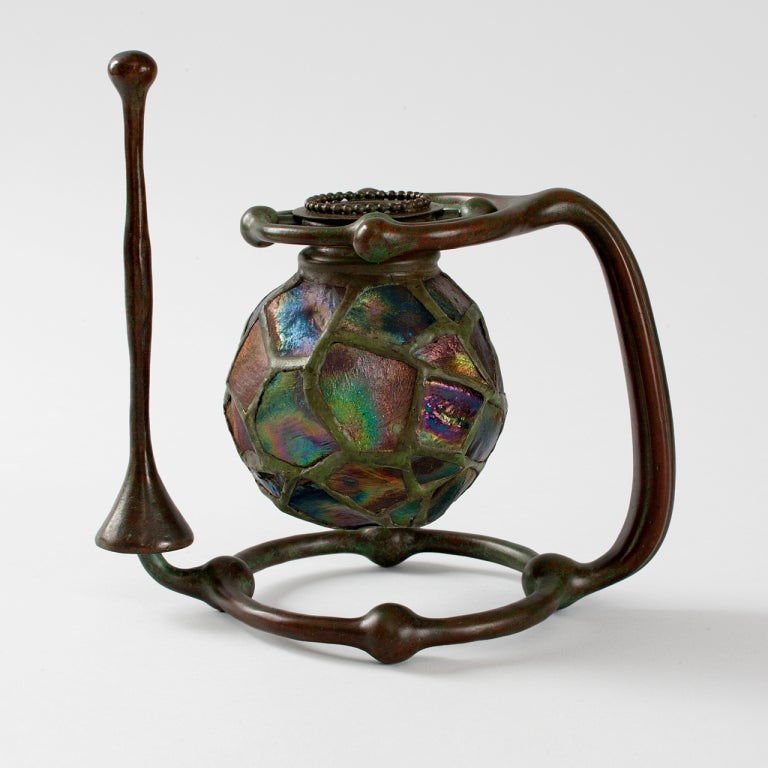 A Tiffany Studios New York  favrile and turtleback tile glass and patinated bronze gimbal candlestick with snuffer.

A similar piece is  pictured in: Tiffany Lamps and Metalware: An illustrated reference to over 2000 models, by Alastair Duncan,