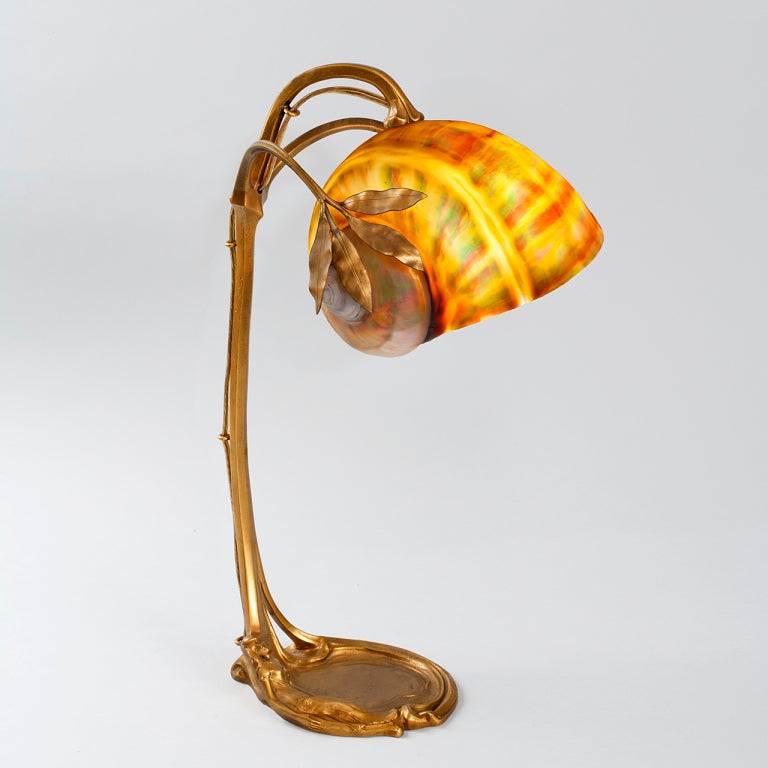 An Austrian Art Nouveau gilt bronze and nautilus shell desk lamp with a naturalistic floriform base decorated with a sleeping maiden.