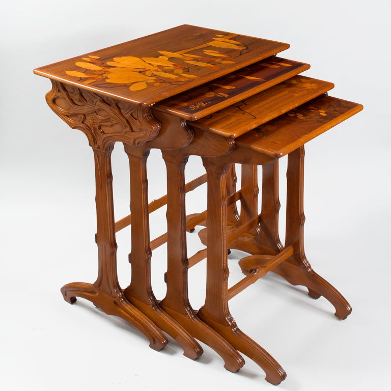 A set of four French Art Nouveau walnut nesting tables, by Emile Gallé. Decorated with fruit wood marquetry carvings of magnolia and butterflies.