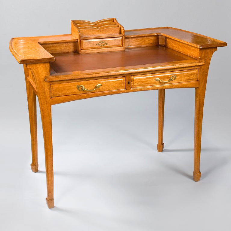 A French Art Nouveau mahogany desk by l'Ecole de Nancy, featuring a hand-tooled leather top, letter rack and bronze drawer pulls with a floral motif.

(MG #12005)
    