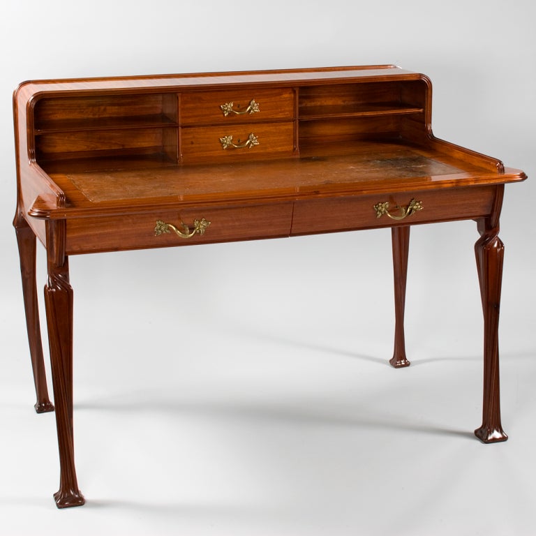 A French Art Nouveau desk by Louis Majorelle, featuring carved mahogany with twisted front legs, two drawers with grape-motif bronze fittings, and the original leather top. Pictured in: Louis Majorelle: Master of Art Nouveau design, by Alastair