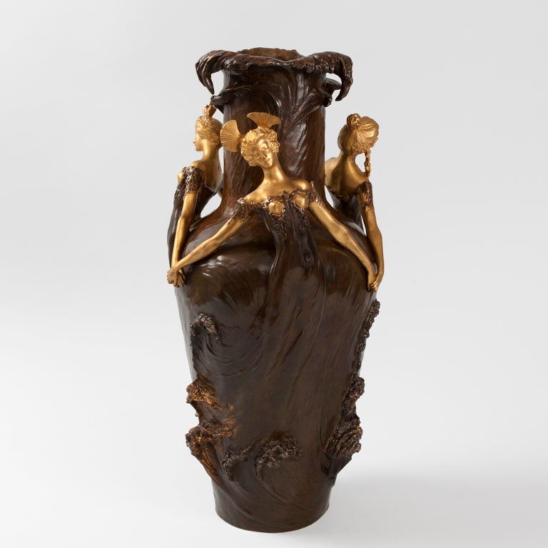 A gilt and patinated figural French Art Nouveau vase by Louis Chalon. Three bare-breasted maidens holding hands surround the body of the vase. The figures emerge from the wave crests of an oceanscape. Their diaphanous robes blend in with the watery