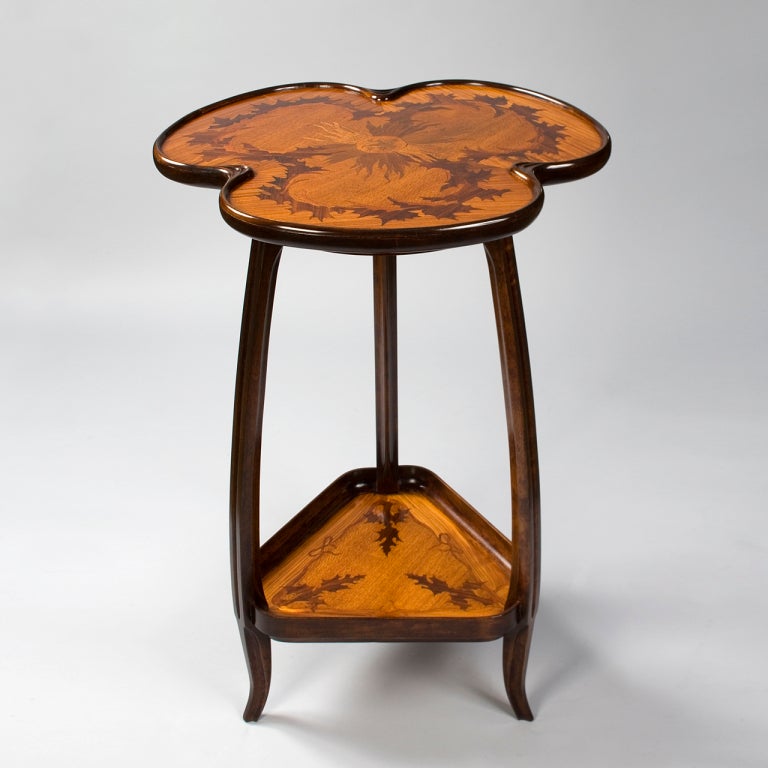 A French Art Nouveau two-tiered table by Louis Majorelle, featuring inlaid marquetry depicting sunflowers on the upper tier, and a leaf pattern on the lower. A model of this table is in the permanent collection of the Musée de l’Ecole de Nancy.