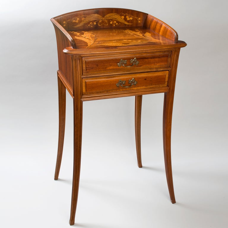 A French Art Nouveau wooden night table by Louis Majorelle, featuring a magnificent inlaid marquetry desk top and curvilinear legs.