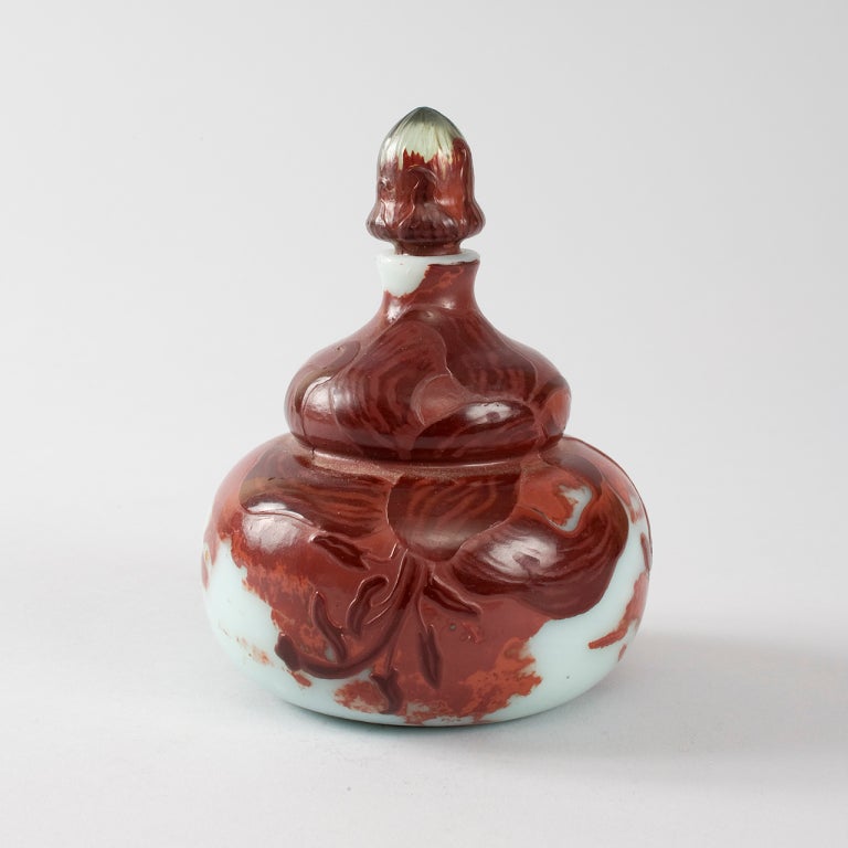 A French Art Nouveau cameo-glass stoppered bottle by Emile Gallé, featuring a decoration of a dark maroon carved lily over a light blue background.

Similar vase pictured in: 
Glas des Art Nouveau by Die Sammlung Gerda Koepff, p. 115.

(MG