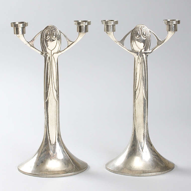 A pair of Austrian Art Nouveau two-armed, polished pewter candlesticks by Joseph Maria Olbrich for Eduard Hueck, Lüdenscheid, with an abstract design, standing on a wide oval base. The shape of the candlestick is reminiscent of a female figure with