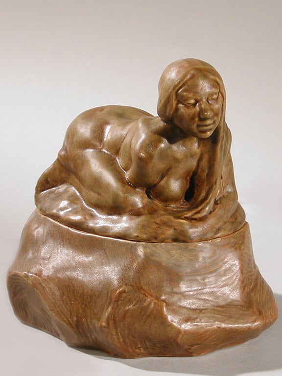 A French Art Nouveau ceramic covered jar by Rupert Carabin, depicting a female nude crouching atop an organic form in a deep brown glaze.  Pictured in: Art Nouveau Sculpture, by Alastair Duncan, p. 20 and in Dynamic Beauty: Sculpture of Art Nouveau