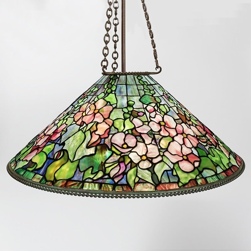 A Tiffany Studios New York glass and bronze “Hollyhock” chandelier, featuring a leaded glass shade depicting a multi-hued array of flower blossoms against a green and blue hued ground. 

Similar chandelier pictured in: The Lamps of Louis Comfort