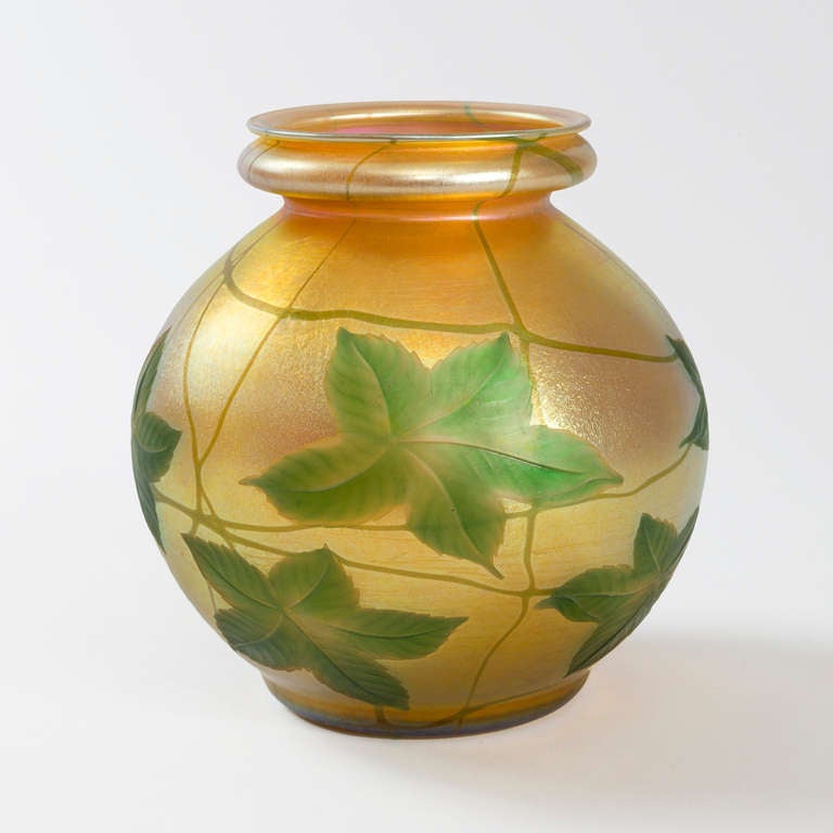 A Tiffany Studios New York Favrile glass vase by Louis Comfort Tiffany with intaglio carved leaf decoration on an iridescent gold ground. Circa 1913.

Favrile is the trade name Tiffany gave to his blown art glass. The name derives from the Latin