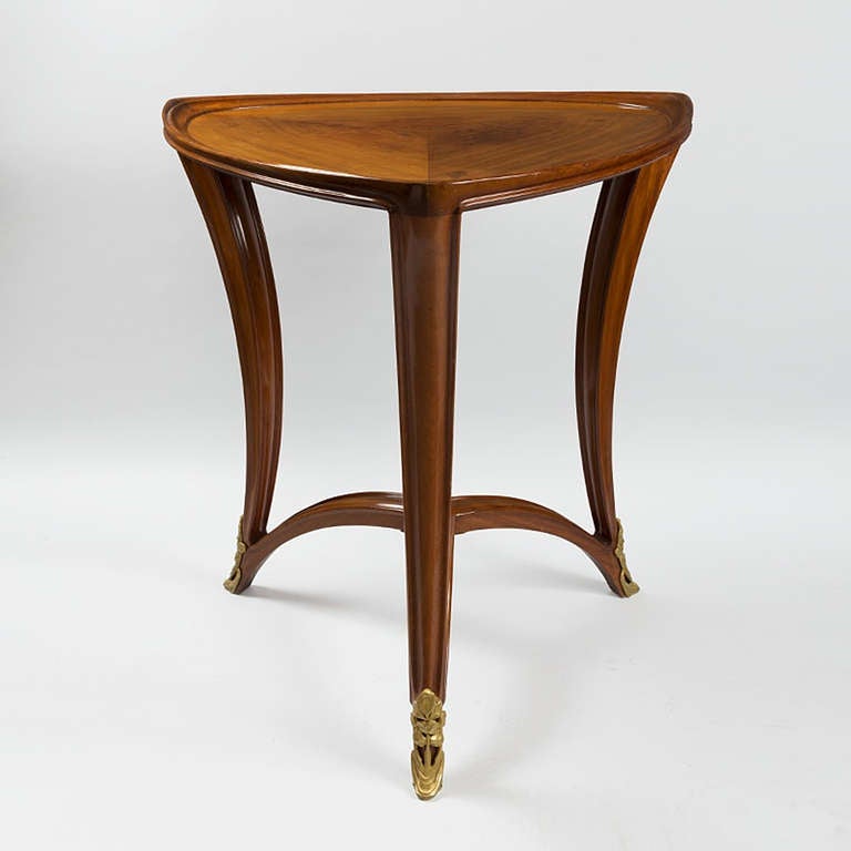 A French Art Nouveau mahogany triangular gueridon with elegant carved decoration and curvilinear design by Louis Majorelle.  Each leg ends in a gilt bronze sabot. Circa 1900.

A similar table is pictured in: Louis Majorelle: Master of Art Nouveau