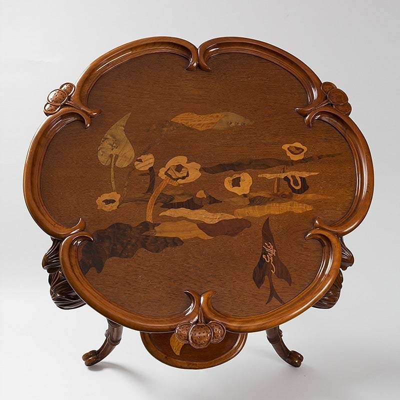 A French Art Nouveau “Libellules” two-tiered table with carved and marquetry decoration by Emile Gallé. Each of the three legs of the table is in the form of a dragonfly with extended wings. Each tier is decorated in marquetry with flowers and