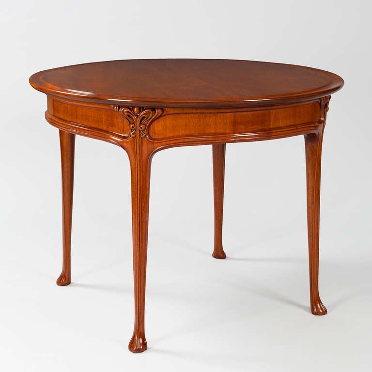 A French Art Nouveau mahogany side table with carved decoration in an abstract curvilinear vegetal motif by Edouard Colonna (1862-1948). Circa 1900. 

Along with Louis Comfort Tiffany, Edouard Colonna was one of the main designers who worked for