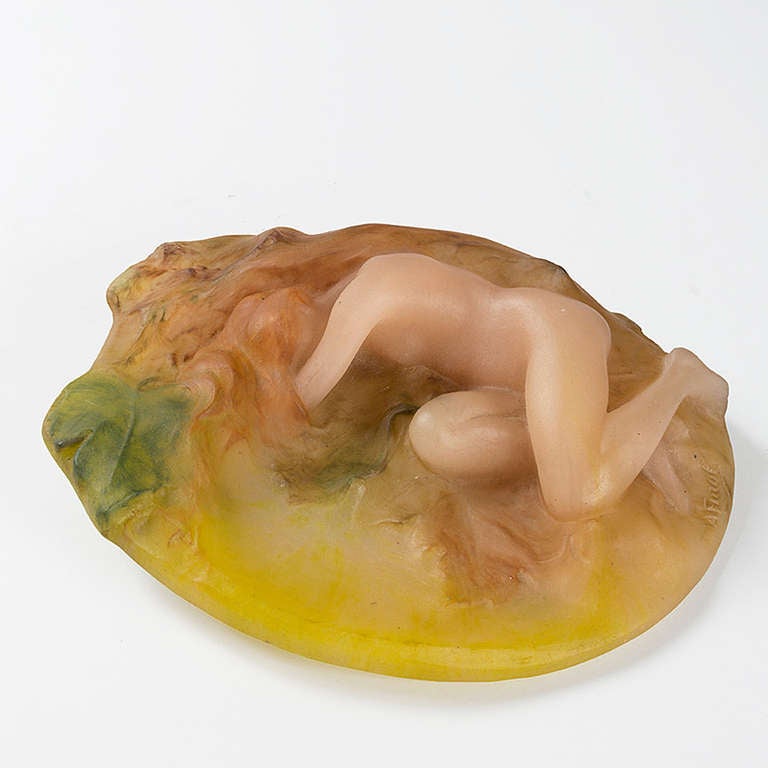 A French Art Nouveau glass pâte de verre paperweight (press-papiers) designed by A. Finot and executed by Amalric Walter, cast in the form of a female nude with light brown hair reclining on a bed of leaves colored in various tones of