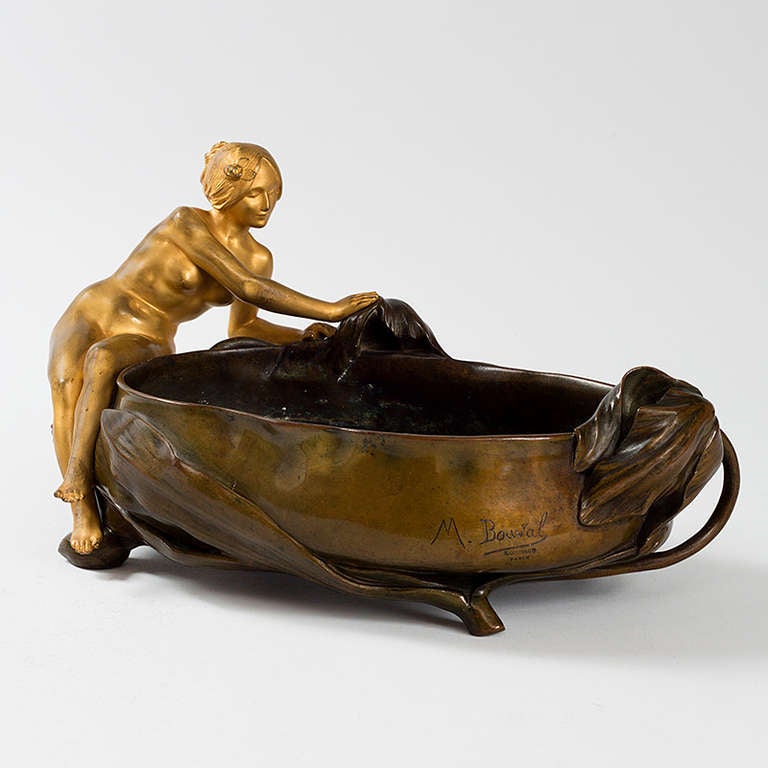 A French Art Nouveau bronze planter, “Nue Assise,” by Maurice Bouval, featuring a gilt bronze nude on the side of a patinated bronze bowl decorated with wilting blooms. Circa 1900.

Signed, “M. Bouval”. 

(MG #15705)