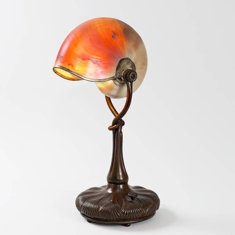 Tiffany Studios, New York ‘Nautilus’ desk lamp with a nautilus shell suspended within a decorated patinated bronze “Shell” base, circa 1900.

A similar lamp is pictured in: Tiffany lamps and metalware: An illustrated reference to over 2000 models,