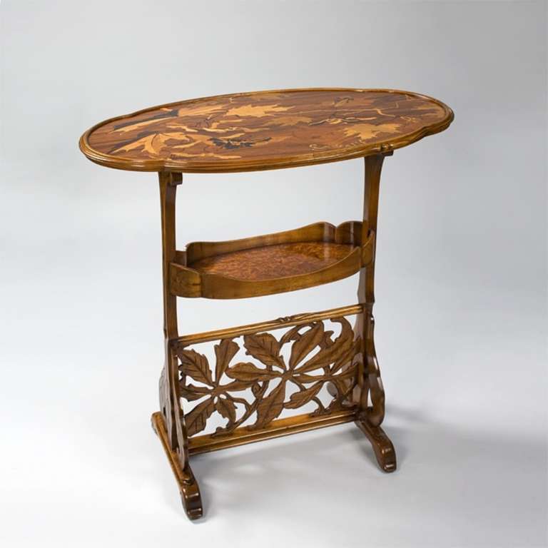 A French Art Nouveau wooden two-tier table by Emile Gallé, featuring inlaid marquetry on the top and intricate carvings in a vegetal motif on the bottom panel, circa 1900. Signed, 