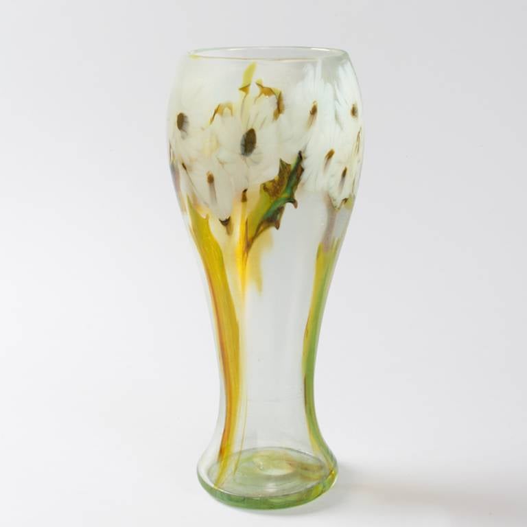 A Tiffany Studios, New York favrile “paperweight” glass vase decorated with a band of white daisies with long green stems and enhanced with red accents, circa 1900. 

The paperweight technique involved fusing thin rods of transparent glass in a