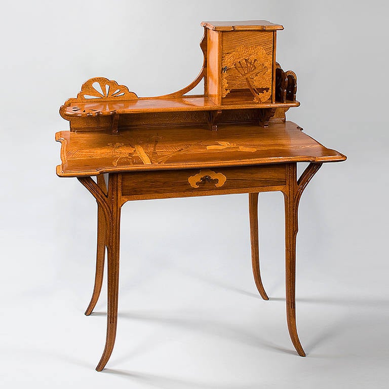 A French Art Nouveau lady’s writing desk, “Aux Ombelles,” by Emile Gallé, featuring fruitwood marquetry depicting a landscape with ombelles carved in a pierced top, circa 1900. Signed “Gallé.” Examples of Gallé’s “ombelles” furniture are pictured