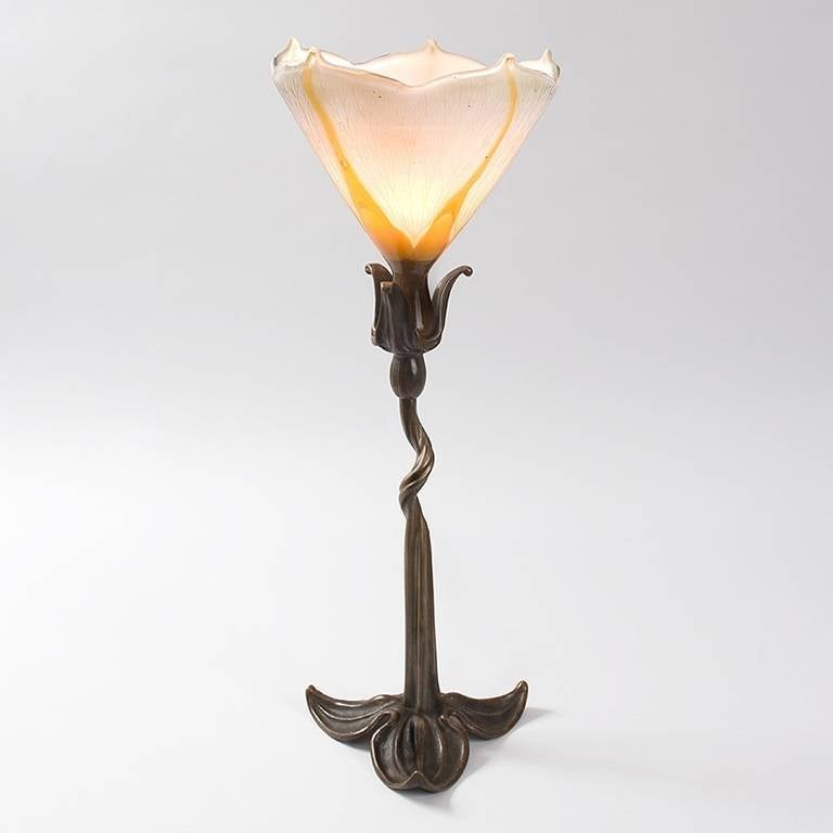 A French Art Nouveau glass and bronze table lamp by Emile Gallé featuring a fire-polished cameo  glass shade in the shape of a blossoming flower atop a patinated bronze organic base. Circa 1900. Signed, “Galle”.  Similar model pictured in The Paris