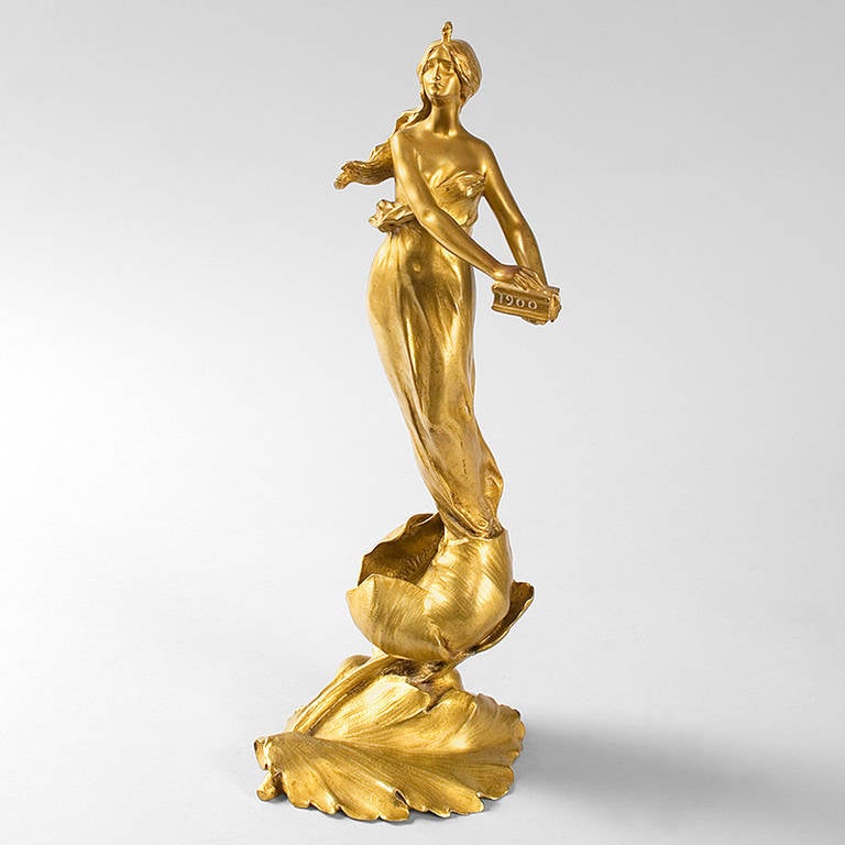 A French Art Nouveau gilt bronze sculpture by Maurice Bouval, featuring a stylized maiden emerging from a flower bulb, holding a box with the inscription “1900.” circa 1900. Pictured in: Dynamic Beauty: Sculpture of Art Nouveau Paris, by Macklowe