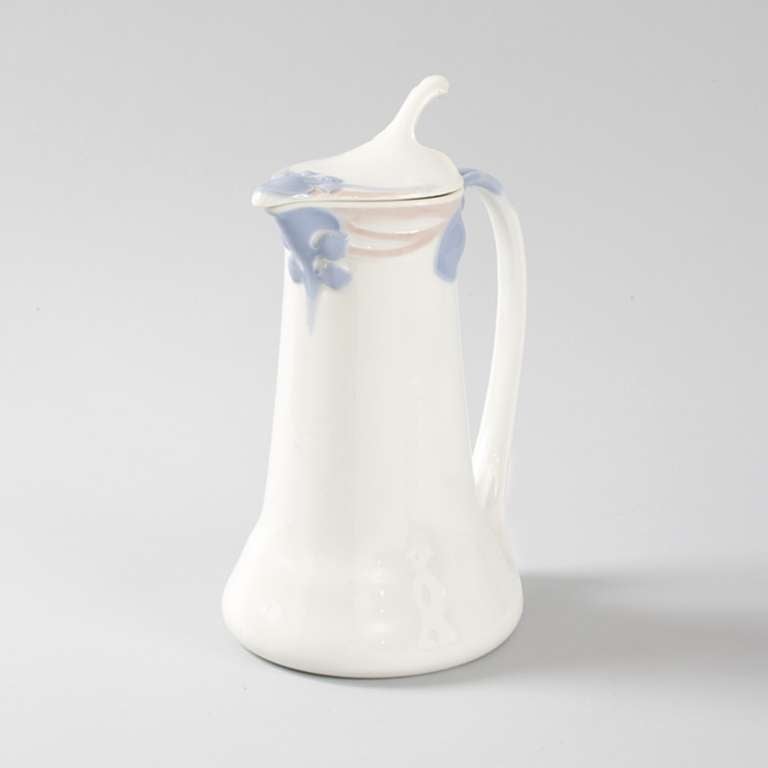A French Art Nouveau pitcher with hinged lid by Maurice Dufrène.   The pitcher features pink and blue floral decoration surrounding the lid and at the top of the handle. Circa 1902. 

A similar pitcher is pictured in: The Paris Salons 1895-1915,