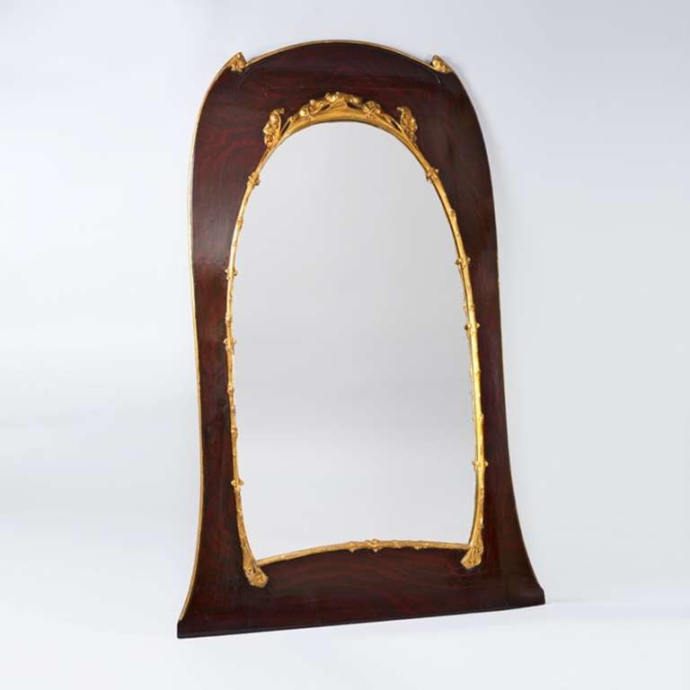 A French Art Nouveau faux mahogany and gilt wood mirror by Hector Guimard. Guimard's mirrors are exceptionally rare, and are desired because they are particularly architectural. For this piece, Guimard decorated a traditional arch motif with foliate