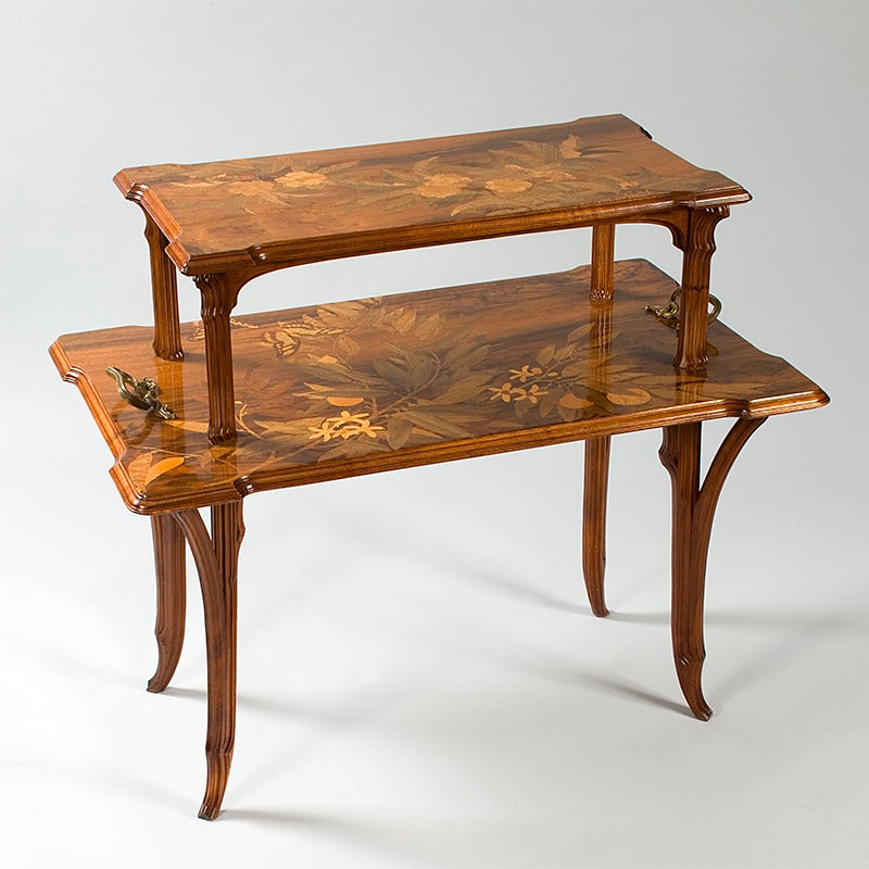 A French Art Nouveau two-tier marquetry wood table with bronze handles, by Emile Gallé, depicting flowers and butterflies in inlaid wood, circa 1900.

A similar table is pictured in: Gallé furniture, by Alastair Duncan and Georges de Bartha,