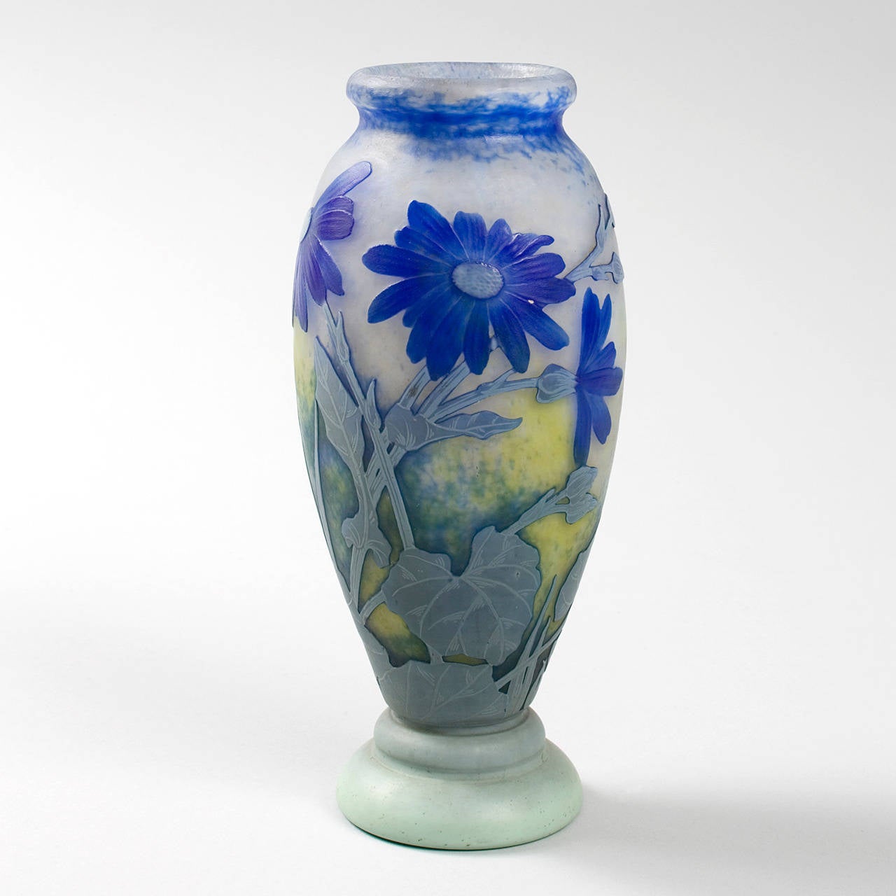 Vaso in vetro cammeo francese Art Carved intagliato a ruota di Daum, con decorazione di fiori blu e steli e foglie di colore azzurro e grigio su un fondo opaco screziato di bianco e giallo, 1910 circa.

Firmato 