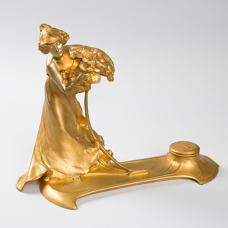 A French Art Nouveau lighted gilt bronze sculpture by Charles Korschann, depicting a woman holding a bouquet of flowers on a tray with an inkwell on the opposite side, circa 1900. Pictured in: Art Nouveau and Art Deco lighting, by Alastair Duncan,