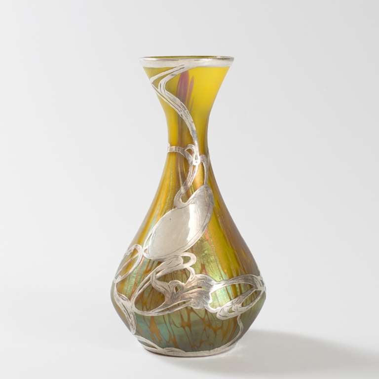 A Bohemian Jugendstil glass vase  with aqua and rose iridescent oil spot decoration against a yellow background by Loetz. The vase is further ornamented with silver overlay in an Art Nouveau vegetal motif  with a center cartouche that has not been