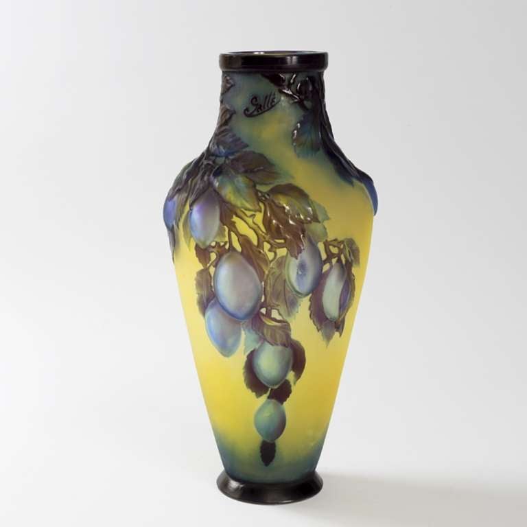 A French Art Nouveau mold blown cameo glass “Plum” vase by Emile Gallé. The applied blue and purple fruits rest on brown leaves, all on a yellow ground.  Circa 1900.

A similar vase is pictured in: Glass by Gallé, by Alastair Duncan and Georges de