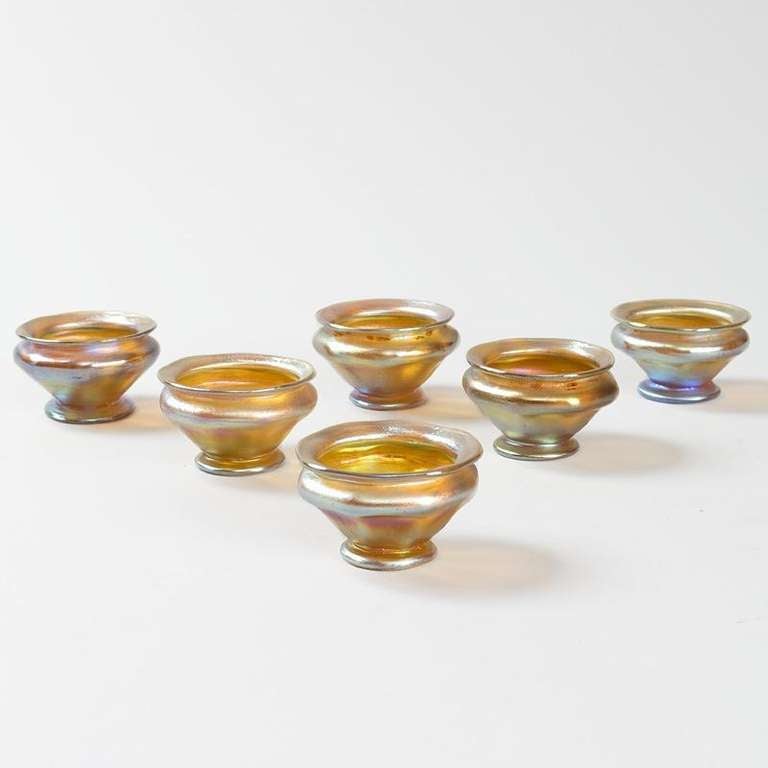 Six Tiffany Studios New York golden iridescent Favrile glass salt dishes.

Favrile is the trade name Tiffany gave to his blown art glass. The name derives from the Latin word fabrilis, meaning 