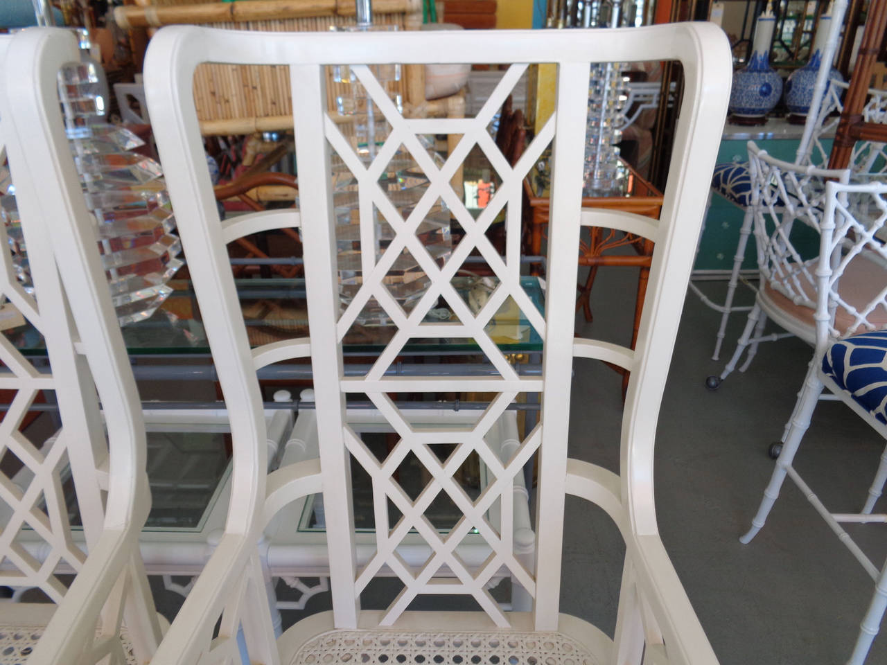 Pair of Hollywood Regency Style Fretwork Wing Chairs with caned seats in good as found vintage condition. There are scuffs, scrapes and chips to the as found finish.