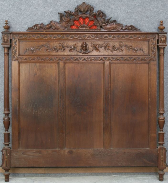 A French Brittany Bed in chestnut with high-quality carvings of a rural village scene on the footboard and a man and woman in traditional Brittany dress on the headboard. This bed is full-size, but could be converted to queen-size for an additional