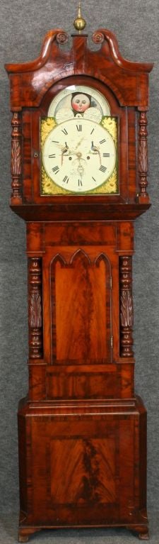 A beautiful and grand Welsh Tall Case Grandfather Clock in an outstanding flame mahogany case crowned with a swan's neck pediment and ball and spire finial. A pair of carved and turned columns frame the glazed bonnet door. The hand-painted dial has