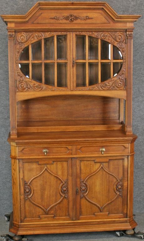 A Renaissance-style Buffet Server China Cabinet Hutch from Germany dating to 1900 in oak with high-quality carvings and an interesting round central glass window