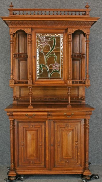 A Renaissance Henry II-style Buffet Server China Cabinet Hutch from France dating to 1900 in oak with a beautiful stained glass panel in the central door featuring flowers
