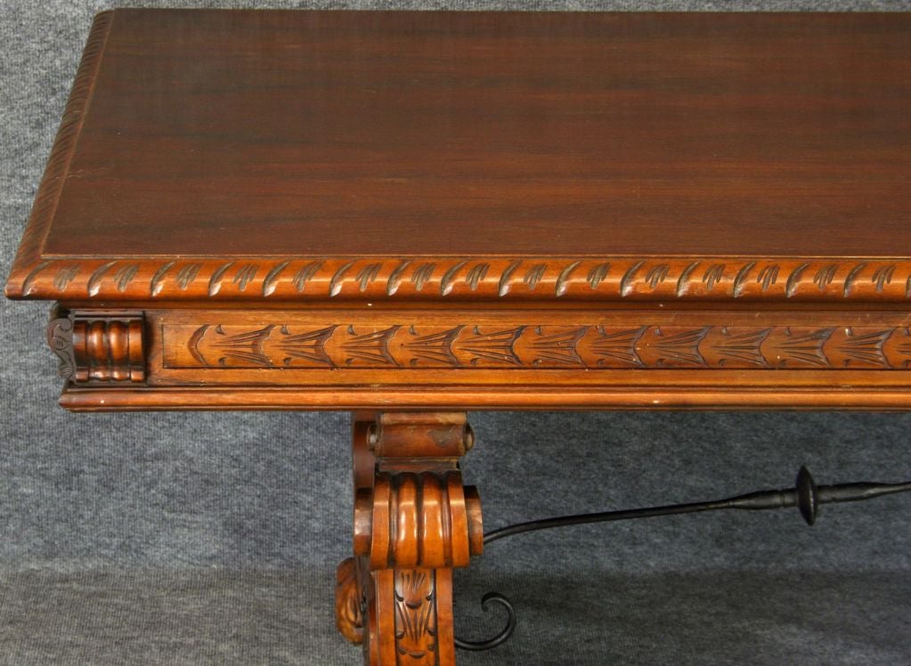 A massive Spanish Renaissance-style Dining Table in Mahogany veneer and iron hardware with heavily carved legs and claw feet.