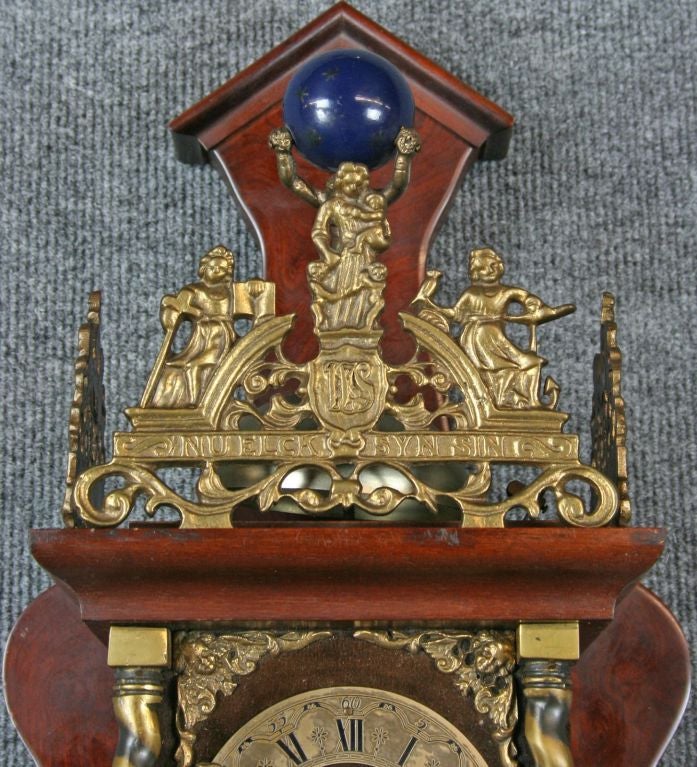 A Vintage Zaandam Zaanse Style Pendulum Wall Clock from Holland dating to 1950 in mahogany and featuring the mythological figure of Atlas carrying the world on his shoulders at the top.